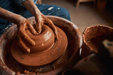 Unrecognized craft woman modeling earthenware product in pottery workshop