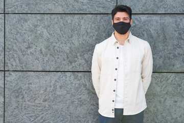 YYoung masked man standing near a wall, covid and coronavirus concept