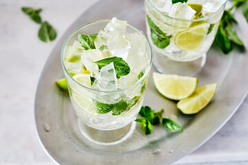Cold refreshing summer lemonade mojito in a glass on a grey concrete or stone background. Copy space.