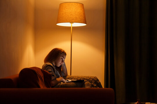 Tired young woman using tablet in evening