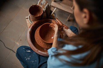 Fototapeta na wymiar Charming focused ceramicist modeling tableware in pottery workshop