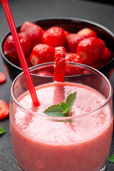 Strawberry milkshake with peppermint in a glass on a dark stone background. Healthy eating for breakfast and snacks.