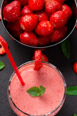 Strawberry milkshake with peppermint in a glass on a dark stone background. Healthy eating for breakfast and snacks.