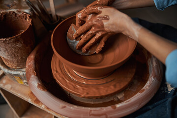 Unrecognized ceramicist modeling non painted tableware in pottery workshop
