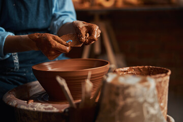 Fototapeta na wymiar Elegant arms of female artisan in clay while making bowl in pottery workshop