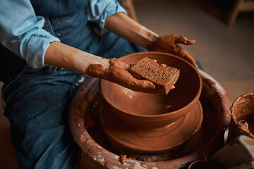 Unrecognized ceramicist in apron working with fresh wet clay i pottery workshop