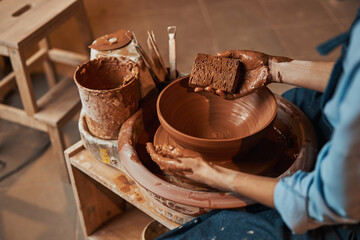 Unrecognized female artisan squeezing fresh wet clay in art studio on pottery wheel