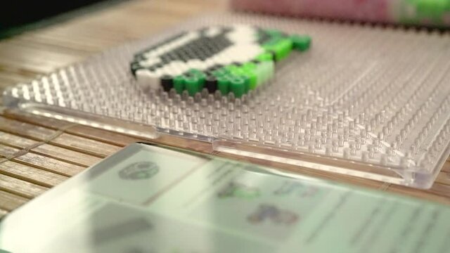 Persona armando patr&oacute;n con perlas de pl&aacute;stico par planchar