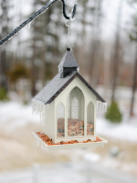 Bird feeder with long icicles hanging from edges after an ice storm