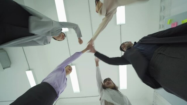 Group of Asian successful business people stacking hands together to cheer up team together in meeting, communicate, discuss, and working with colleagues in office. People lifestyle.Corporate teamwork