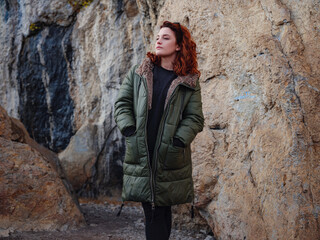 a redheaded woman walking along a mountain road in early spring