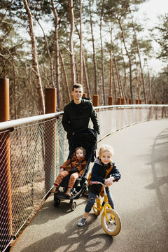 Father walking on a bridge in the forest with his two children