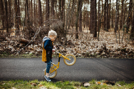 Little Blond Boy In The Forest With A Yellow Bicycle Doing Crazy Moves