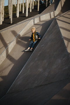 Blond boy playing on a concrete playground outdoors