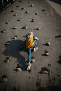 Blond boy playing on a concrete boulder playground outdoors