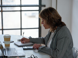 Female writing notes during conference online.