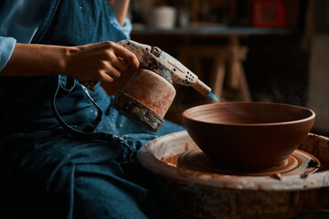 Image of process modeling ceramic bowl with special instrument in pottery workshop - obrazy, fototapety, plakaty