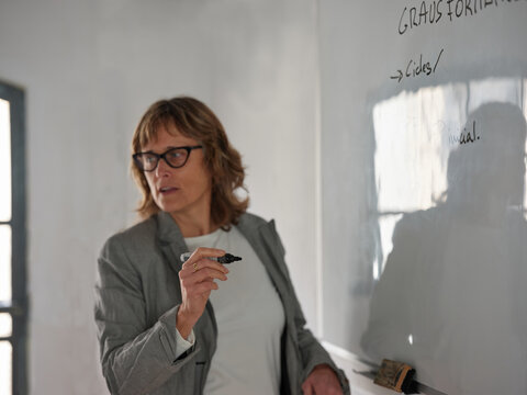 50`s woman director drawing on white board.