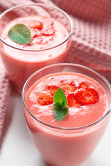 Fresh strawberry milkshake decorated with berries and mint on a light background in pastel colors, space for text, the concept of a healthy breakfast, diet and good nutrition.