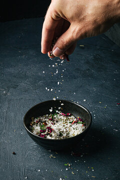 Hand sprinkling salt over a ceramic bowl
