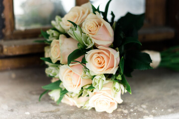 The bride's bouquet lies on the windowsill, light roses in a bouquet close-up