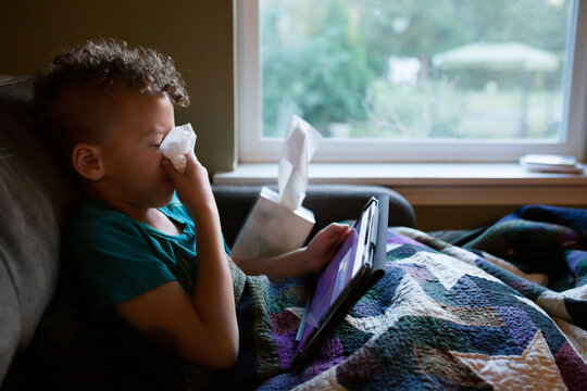 Sick boy blows nose with tissue