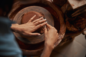 Picture of delicate process of manufacturing clay product on pottery wheel in modern workshop