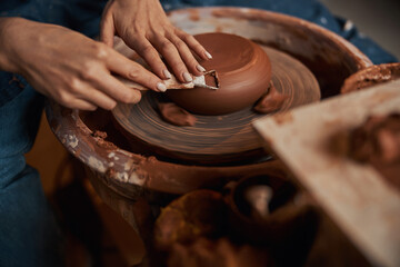 Unrecognized female arms making earthenware tableware in pottery workshop