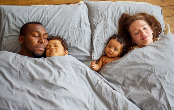 Happy multi-racial family sleeps at home