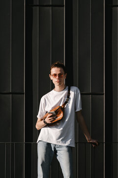 Young man leaning on fence on street