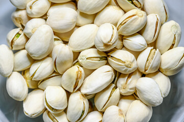 Close-up top view a pile of beans it has a white nut shell dry and hard of Pistachio, Pistache or Pistacia vera in a bowl food delicious salty snack