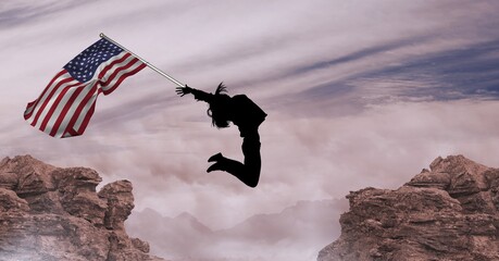 Composition of silhouetted figure jumping holding american flag against mountains and cloudy sky