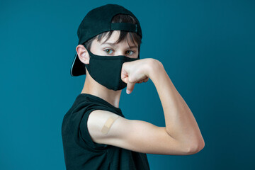Teenage boy with bandage plaster on his arm makes fist and flexes her bicep after vaccination....