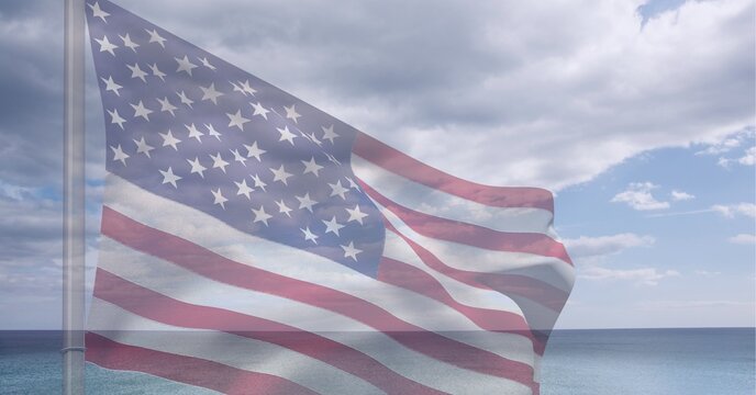 Composition of billowing american flag on flagpole over sea and cloudy blue sky