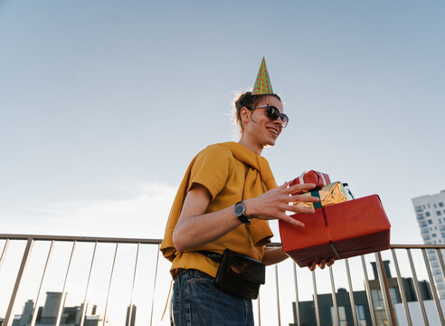 Young man with birthday gifts on rooftop