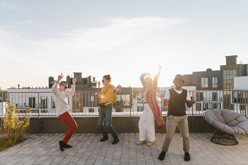 Energetic young friends dancing on rooftop