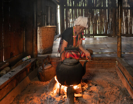 A portrait of karen tribe woman boiling water by using traditional kettle and fire, water heater at wooden kitchen at local home. People lifestyle.