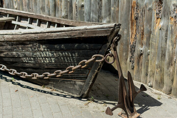 Detail of an old wooden boat's bow by the river with hanging chain and anchor