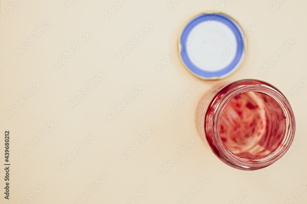 Poster top view of an open empty strawberry jam jar with lid isolated on light brown background