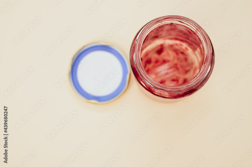 Poster top view of an open empty strawberry jam jar with lid isolated on light brown background
