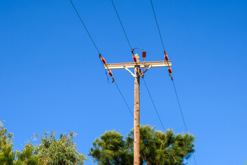 Power lines on a wooden pole, against a blue sky background. Paros island, Greece