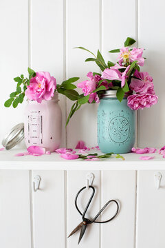 Pink roses on shelf with scissors