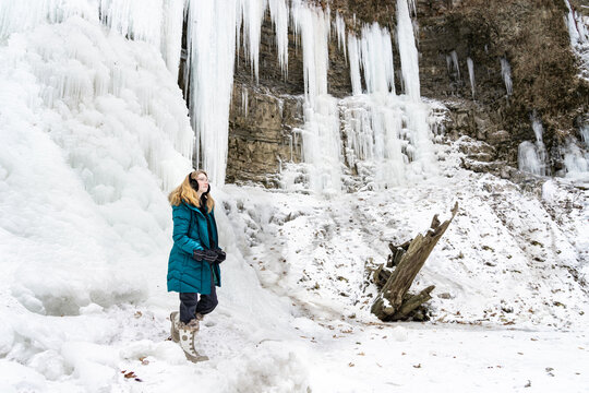 Teen Girl Hiking and Exploring a Frozen Waterfall in Winter