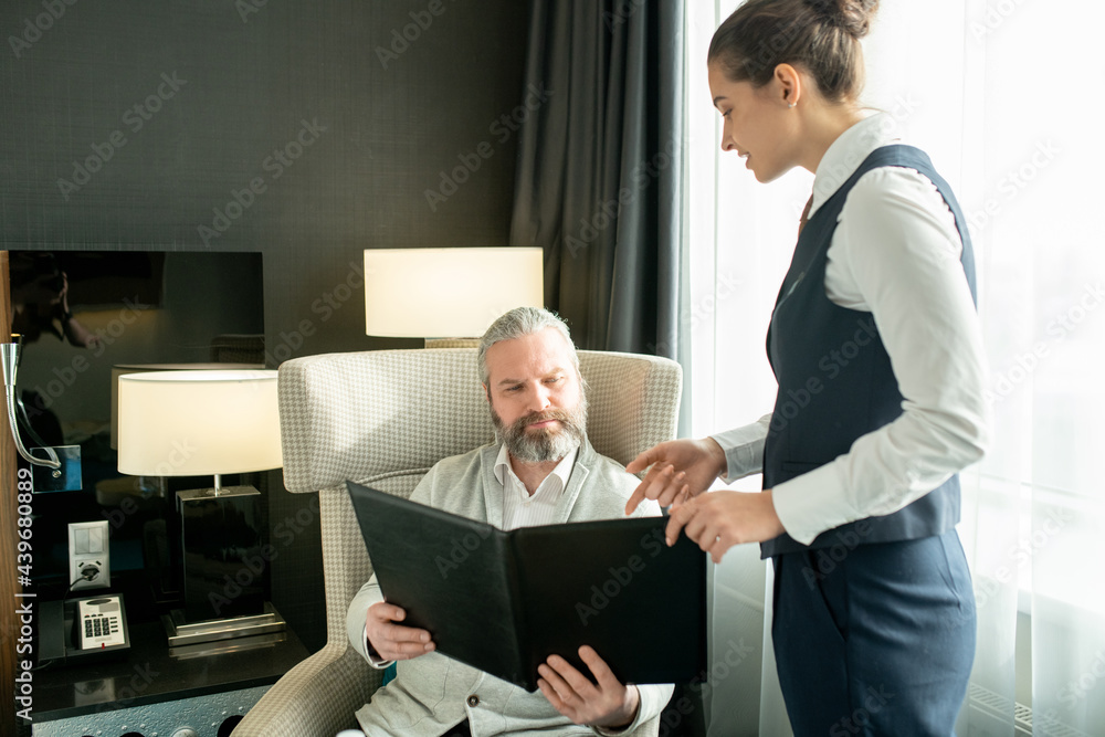 Wall mural young female manager recommending something from menu to mature man