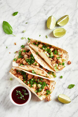 Tacos with meat and herbs, sauce and lime. National Mexican street food. On a light background.
