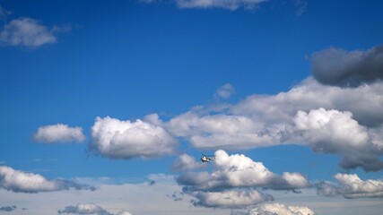 View of the blue sky with white clouds and a flying helicopter.