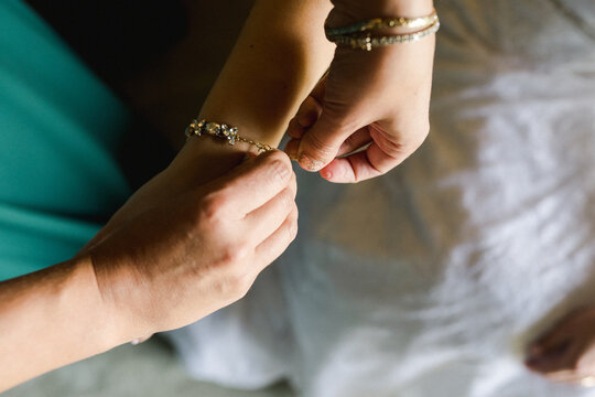 bride getting help putting bracelet on 