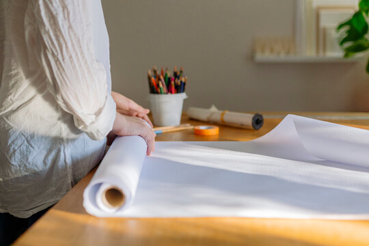 Cropped view of a kid starting a design project and preparing the white roll paper