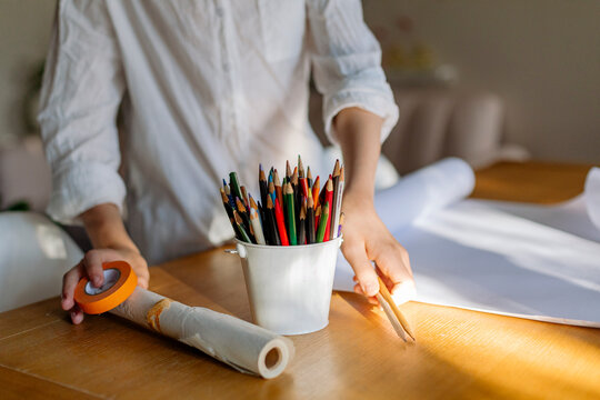 Cropped view of a kid starting a design project and preparing the white roll paper
