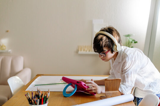 Pre-teen Boy wearing headphones designing a project and using a tablet